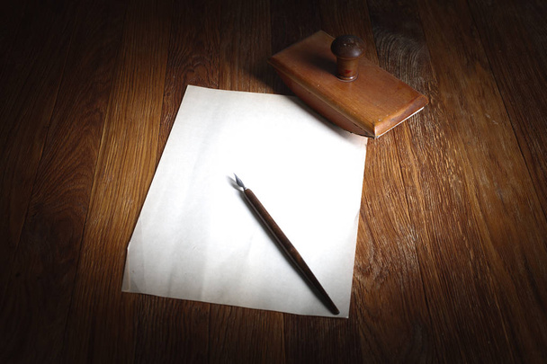 Old fountain pen with inkwell and empty sheet of paper on a wooden table background - 写真・画像