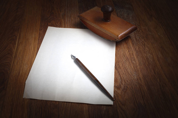 Old fountain pen with inkwell and empty sheet of paper on a wooden table background - 写真・画像