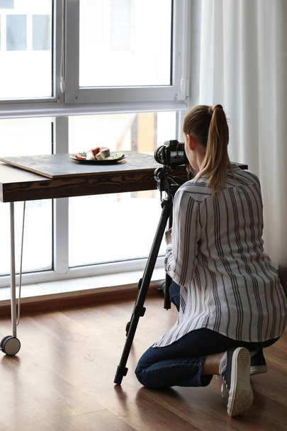 Νεαρή γυναίκα λαμβάνοντας εικόνα των τροφίμων σε επαγγελματικό στούντιο - Φωτογραφία, εικόνα