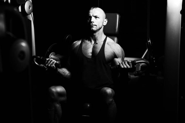 Muscular Fitness Bodybuilder Doing Heavy Weight Exercise For Biceps On Machine With Cable In The Gym - 写真・画像