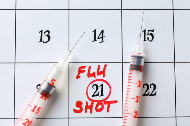 Syringes on calendar with marked date and text FLU SHOT, closeup - Фото, зображення