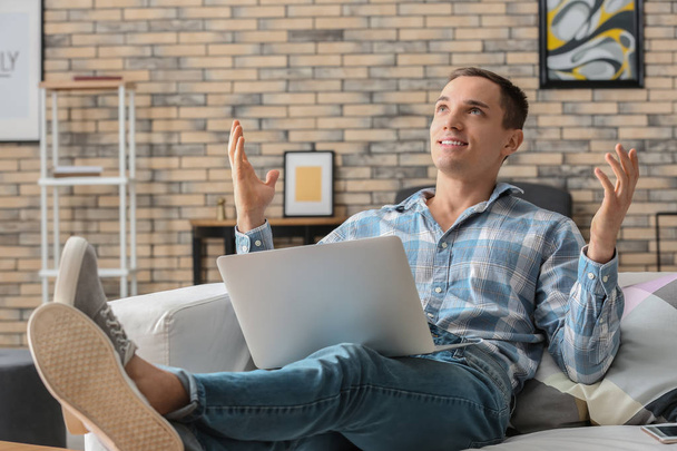 Happy young man with laptop at home - Photo, Image