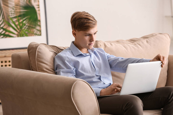 Όμορφος νεαρός άνδρας που εργάζεται σε φορητό υπολογιστή στο σπίτι - Φωτογραφία, εικόνα