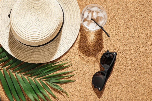 Čepice s sluneční brýle, studený koktejl a tropických listů na korkové pozadí - Fotografie, Obrázek