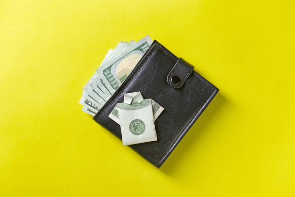 Кошелек с деньгами и рубашкой оригами из долларовой купюры на цветном фоне
 - Фото, изображение