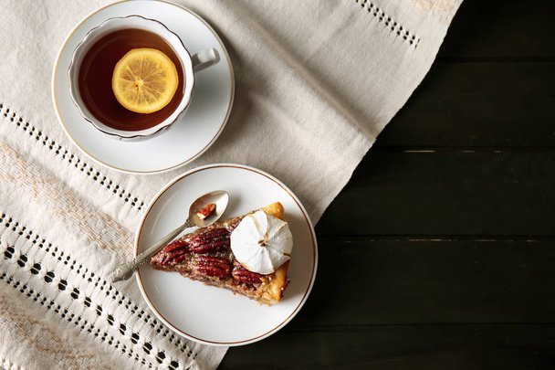 Plate with tasty pecan pie and cup of tea on table - Photo, Image