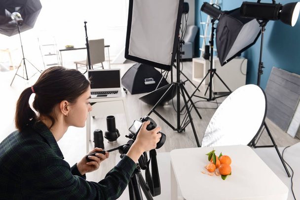Молодая женщина фотографирует свежие мандарины в профессиональной студии
 - Фото, изображение