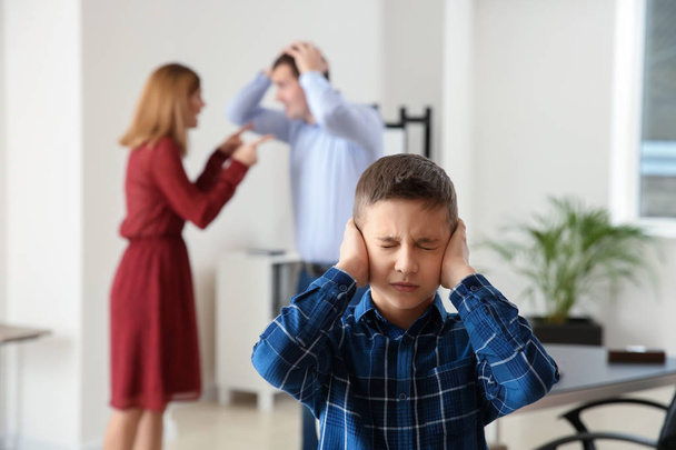 Triste niño pequeño con sus padres en disputa en la oficina del abogado. Concepto de manutención infantil
 - Foto, imagen
