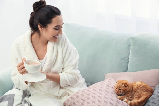 Young woman with cute funny cat drinking coffee at home - Foto, Bild