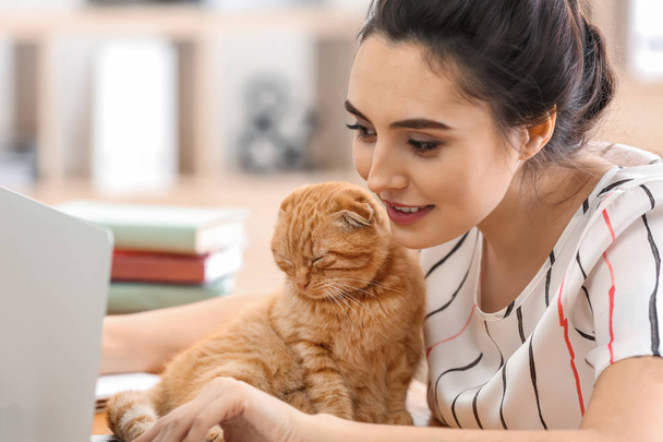 Mujer joven con lindo gato divertido trabajando en casa
 - Foto, Imagen