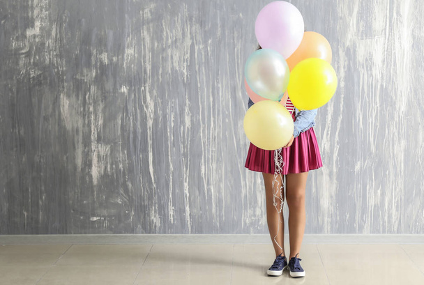 Carefree young woman with balloons near grunge wall - Фото, изображение