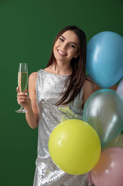 Beautiful young woman with balloons and glass of champagne on color background - Foto, immagini