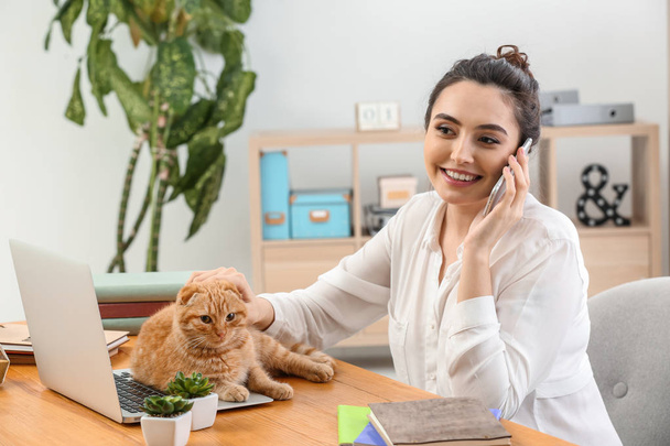 Молода жінка з милою смішною кішкою працює вдома
 - Фото, зображення