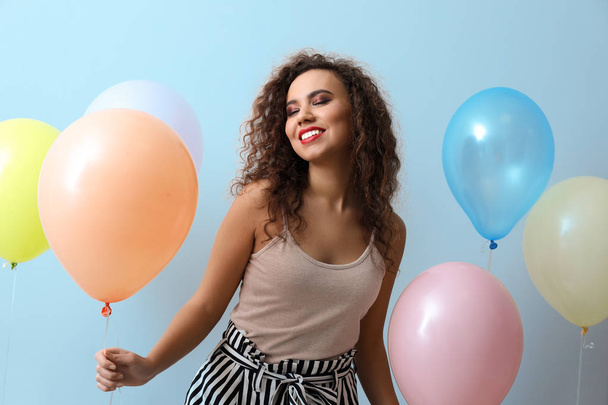 Mooie jonge vrouw met ballonnen op lichte achtergrond - Foto, afbeelding