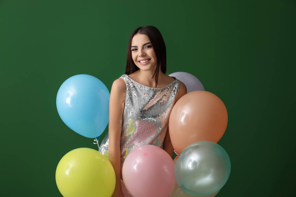 Όμορφη νεαρή γυναίκα με μπαλόνια στο φόντο χρώμα - Φωτογραφία, εικόνα