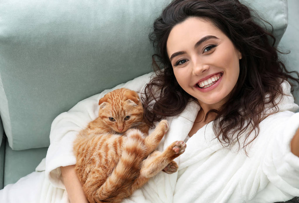 Jonge vrouw nemen selfie met leuke grappige kat thuis - Foto, afbeelding