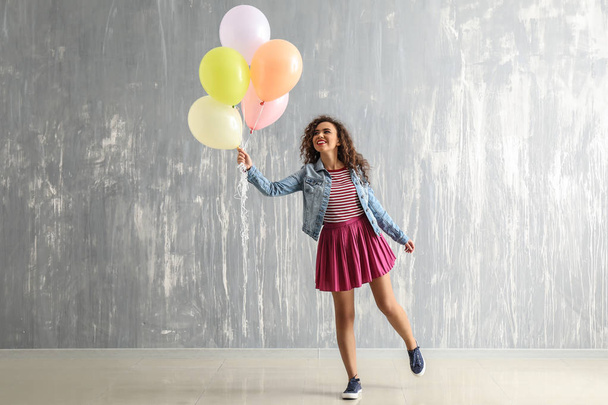Carefree young woman with balloons near grunge wall - Foto, Bild