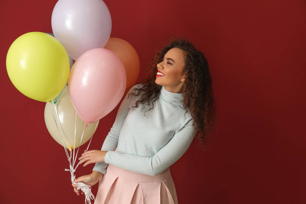 Hermosa mujer joven con globos en el fondo de color - Foto, imagen