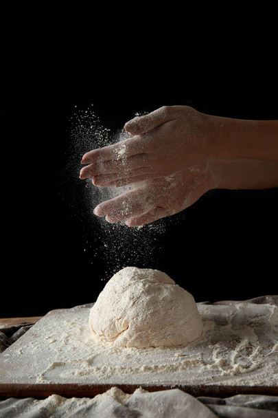 junge Frau bereitet Teig für Brot auf dunklem Hintergrund zu - Foto, Bild