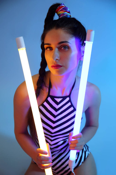 Toned portrait of beautiful young woman with neon lamps on color background - Foto, afbeelding