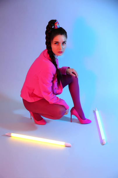 Тонированный портрет красивой молодой женщины с неоновыми лампами на цветном фоне
 - Фото, изображение