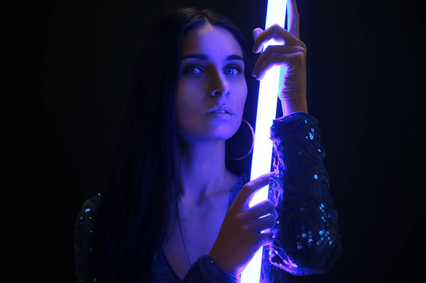 Portrait of beautiful young woman with neon lamp on dark background - Fotoğraf, Görsel
