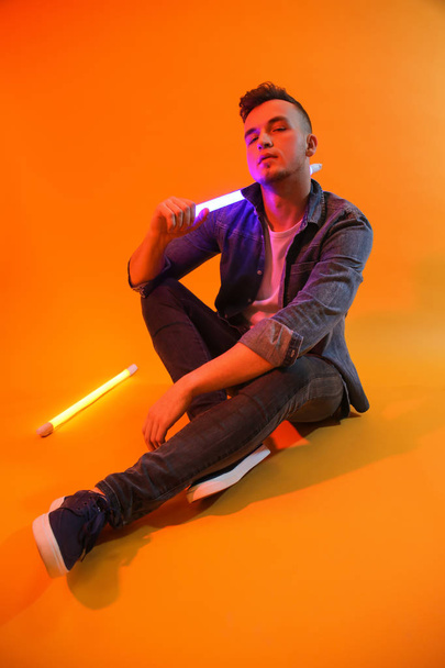 getöntes Porträt eines hübschen jungen Mannes mit Neonlampen auf farbigem Hintergrund - Foto, Bild