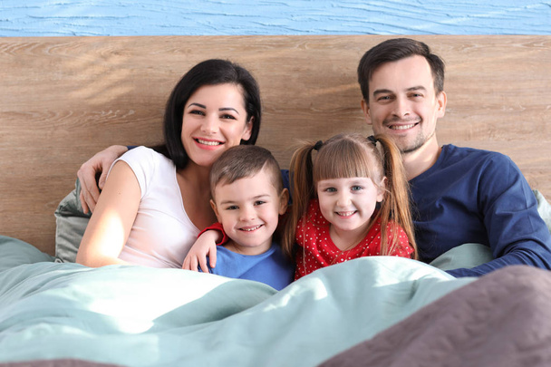 Szczęśliwych rodziców z małymi dziećmi w łóżku w domu - Zdjęcie, obraz