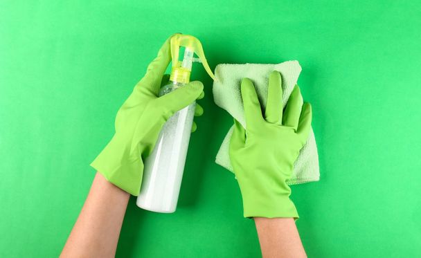 Руки жіночого прибиральника з ганчіркою та миючим засобом на кольоровому фоні
 - Фото, зображення