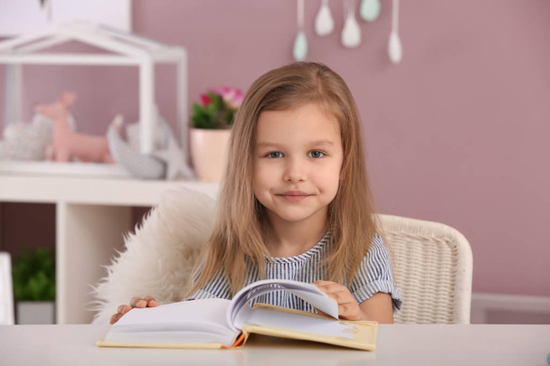Aranyos kislány könyvet olvas otthon. - Fotó, kép