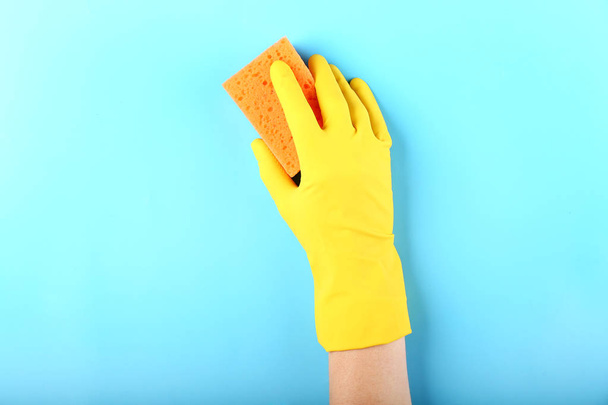 Hand of female janitor with sponge on color background - Photo, Image