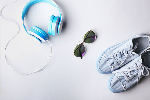 Παπούτσια, γυαλιά ηλίου και ακουστικά επάνω ελαφρύς υπόβαθρο - Φωτογραφία, εικόνα