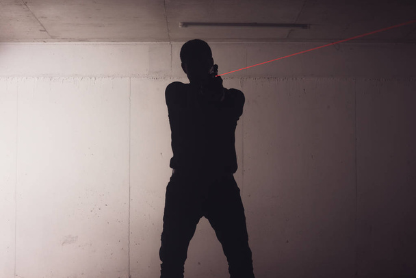 силует озброєного чоловіка тримає пістолет і вказує лазерним променем на ціль
. - Фото, зображення
