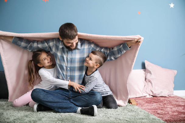 Padre joven con sus hijos jugando en casa
 - Foto, Imagen