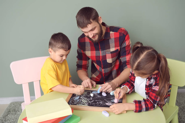 Молодий батько з дітьми малює вдома
 - Фото, зображення
