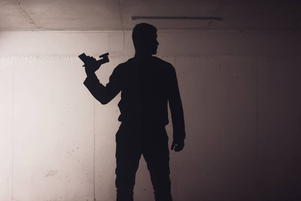 silueta ozbrojeného muže držícího zbraň a mířícího laserovým paprskem na terč. - Fotografie, Obrázek