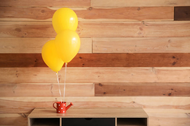 Table et arrosoir avec ballons près du mur en bois
 - Photo, image