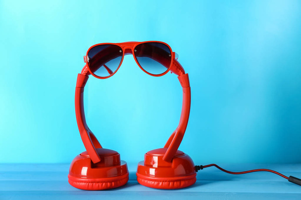 Moderne hoofdtelefoons en zonnebril op kleur achtergrond - Foto, afbeelding