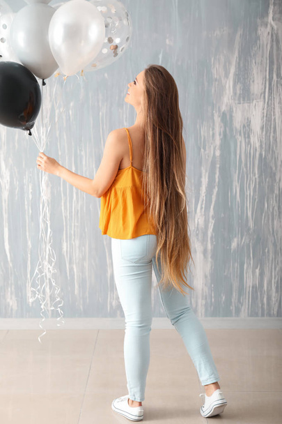 Beautiful young woman with balloons against grunge wall - Photo, Image