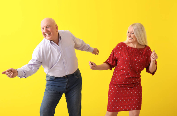 Cute elderly couple dancing against color background - Photo, Image