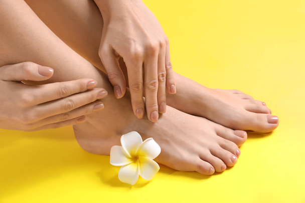 Legs and hands of young woman with beautiful pedicure and manicure on color background - Foto, afbeelding