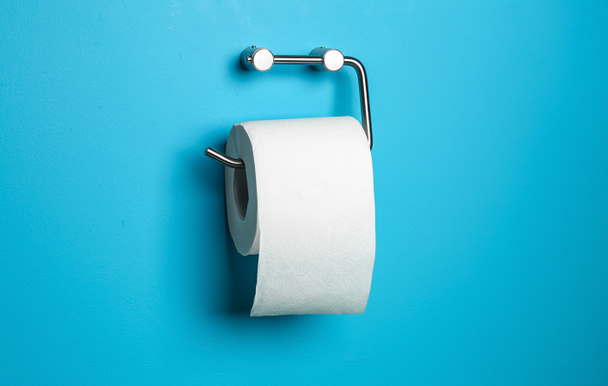 Roll of toilet paper hanging on color wall in restroom - Foto, Imagem