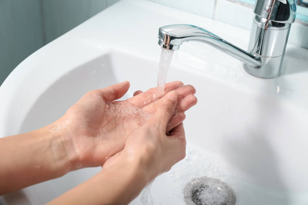 Woman washing hands in sink - Фото, изображение