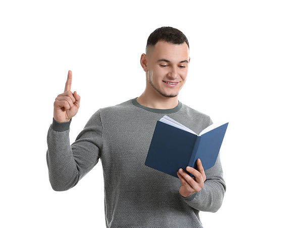 Handsome young man with book and raised index finger on white background - Fotografie, Obrázek
