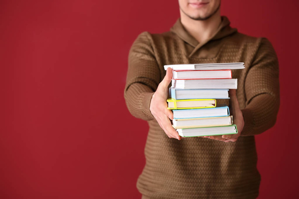 Pohledný mladý muž s knihami na barvu pozadí - Fotografie, Obrázek