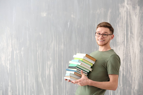 schöner junger Mann mit Büchern über Grunge-Hintergrund - Foto, Bild