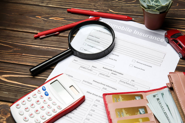 Auto insurance vorm met Vergrootglas, rekenmachine en geld op houten tafel - Foto, afbeelding