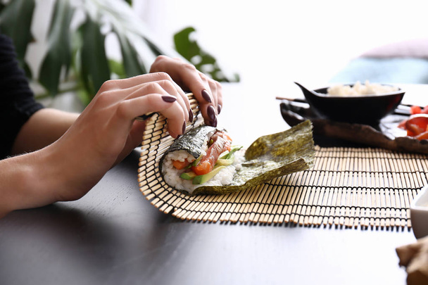 Žena dělat chutné sushi rolls u stolu - Fotografie, Obrázek