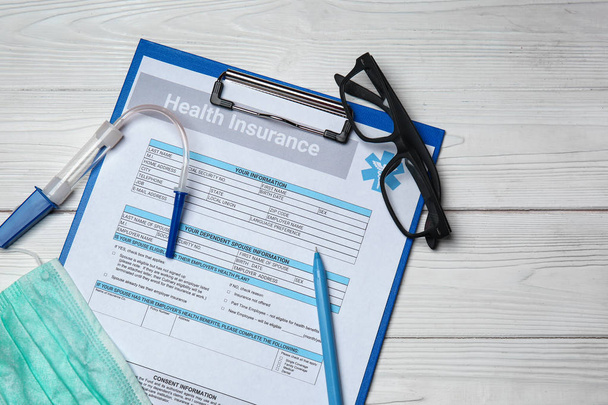 Formulário de seguro de saúde com óculos na mesa branca
 - Foto, Imagem