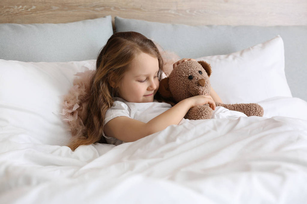 Cute little girl with toy bear in bed - Foto, Imagen
